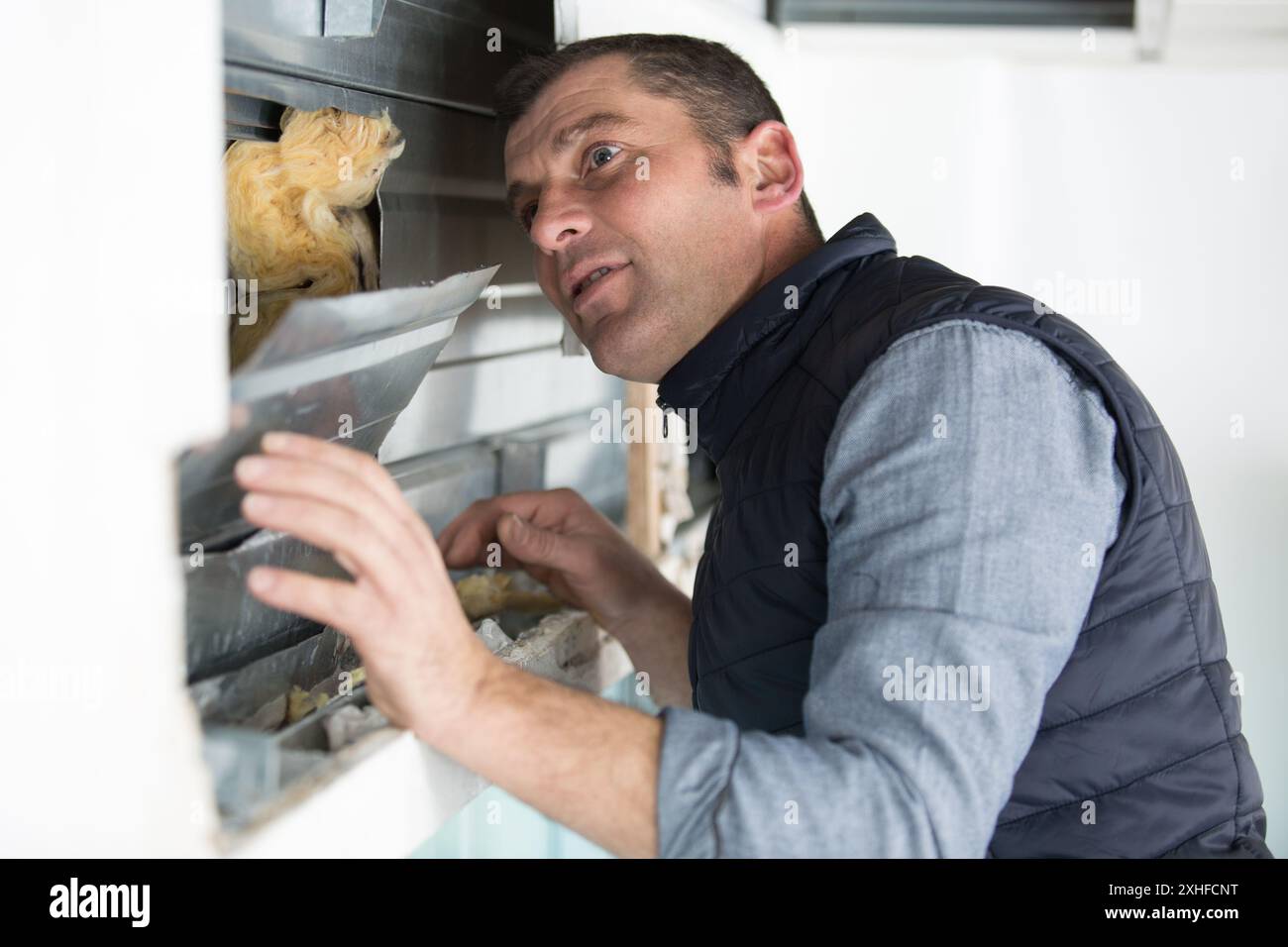 smiling man is fixing a window using a screwdriver Stock Photo