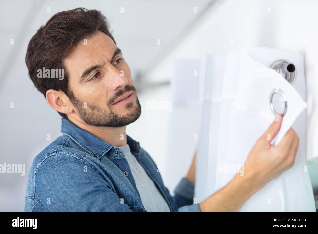 young man installing curtains over window Stock Photo