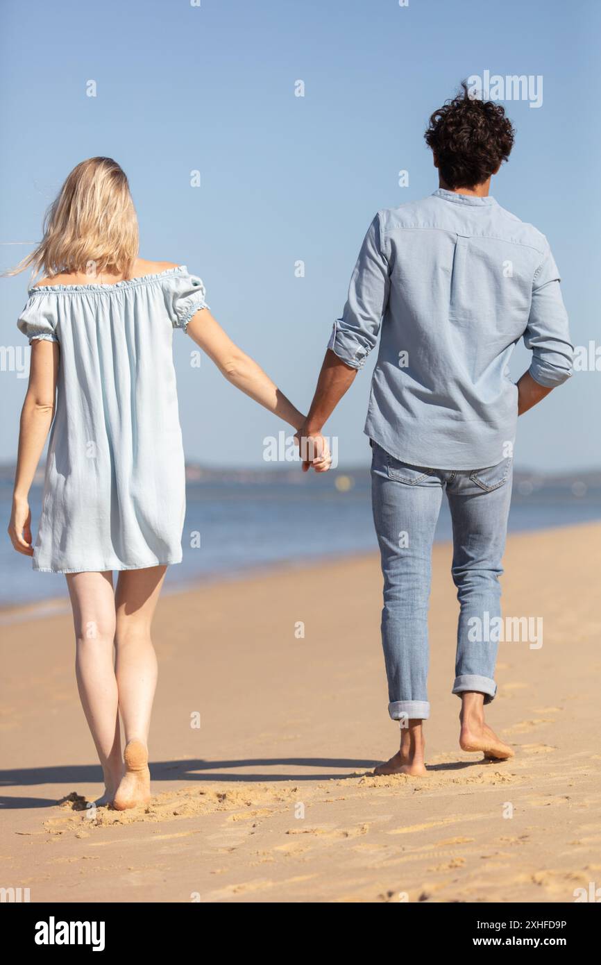 rear view of couple holding hands walking on the beach Stock Photo - Alamy