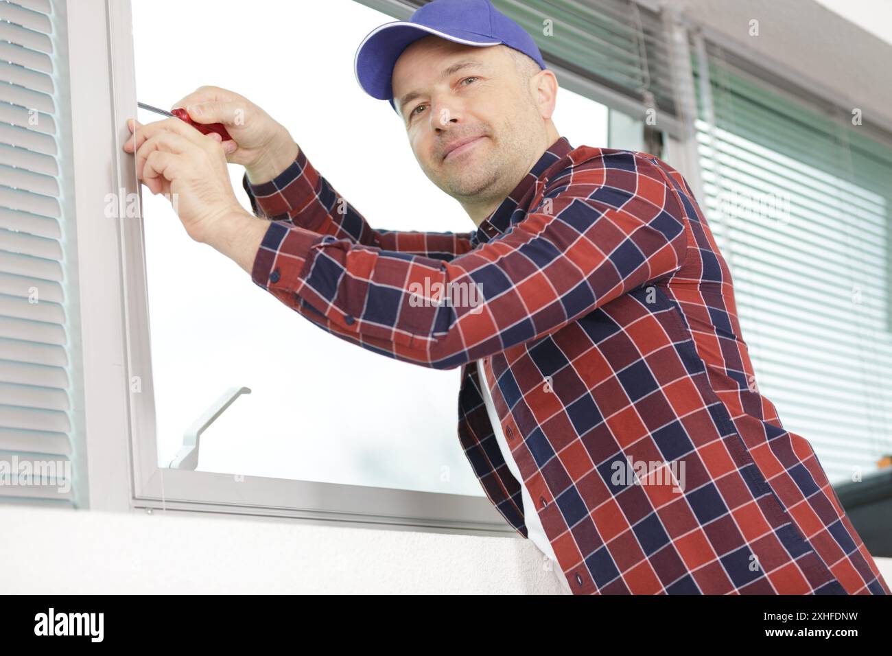 worker fasten the handle to a plastic window Stock Photo