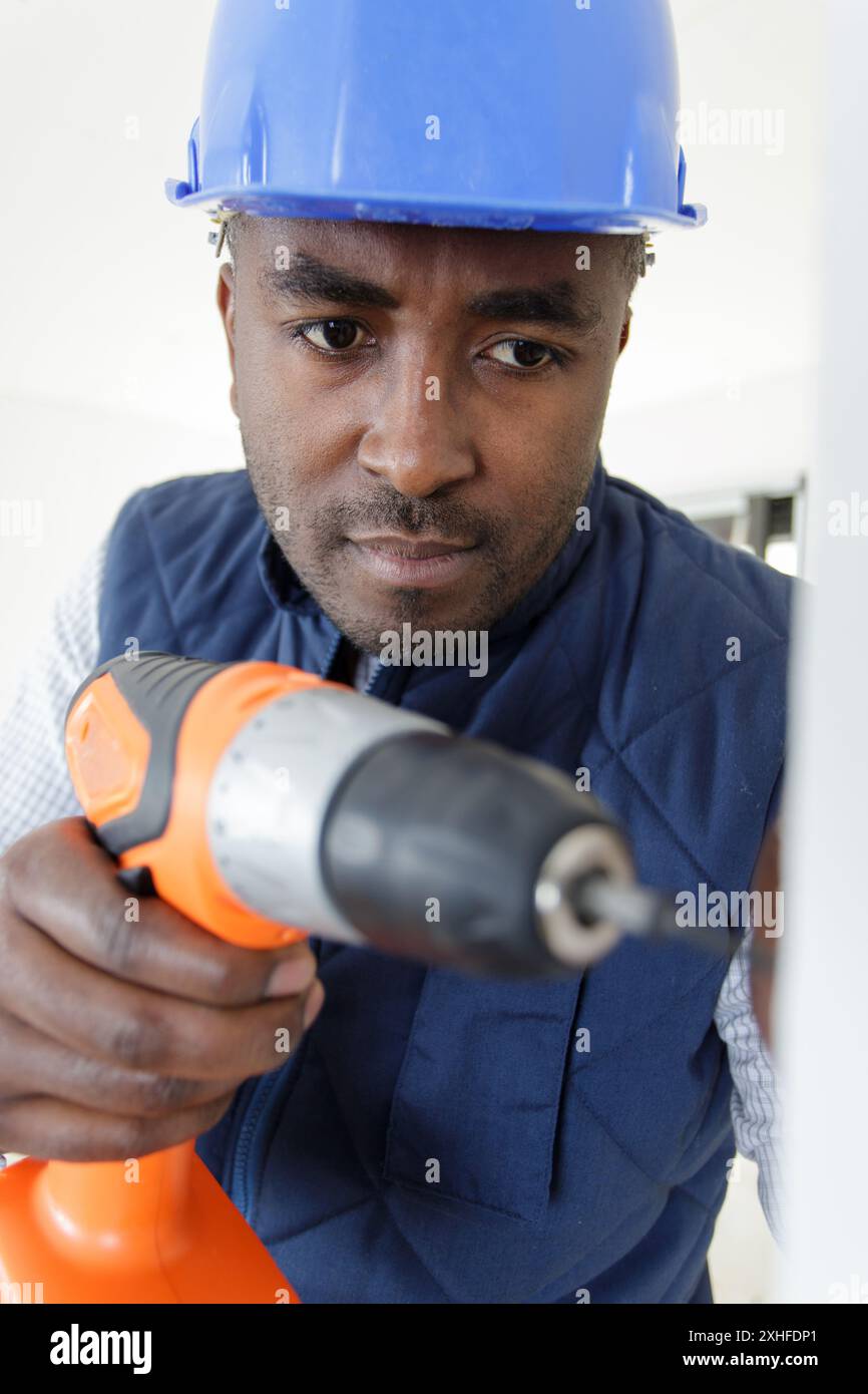 mixed race builder using cordless drill Stock Photo