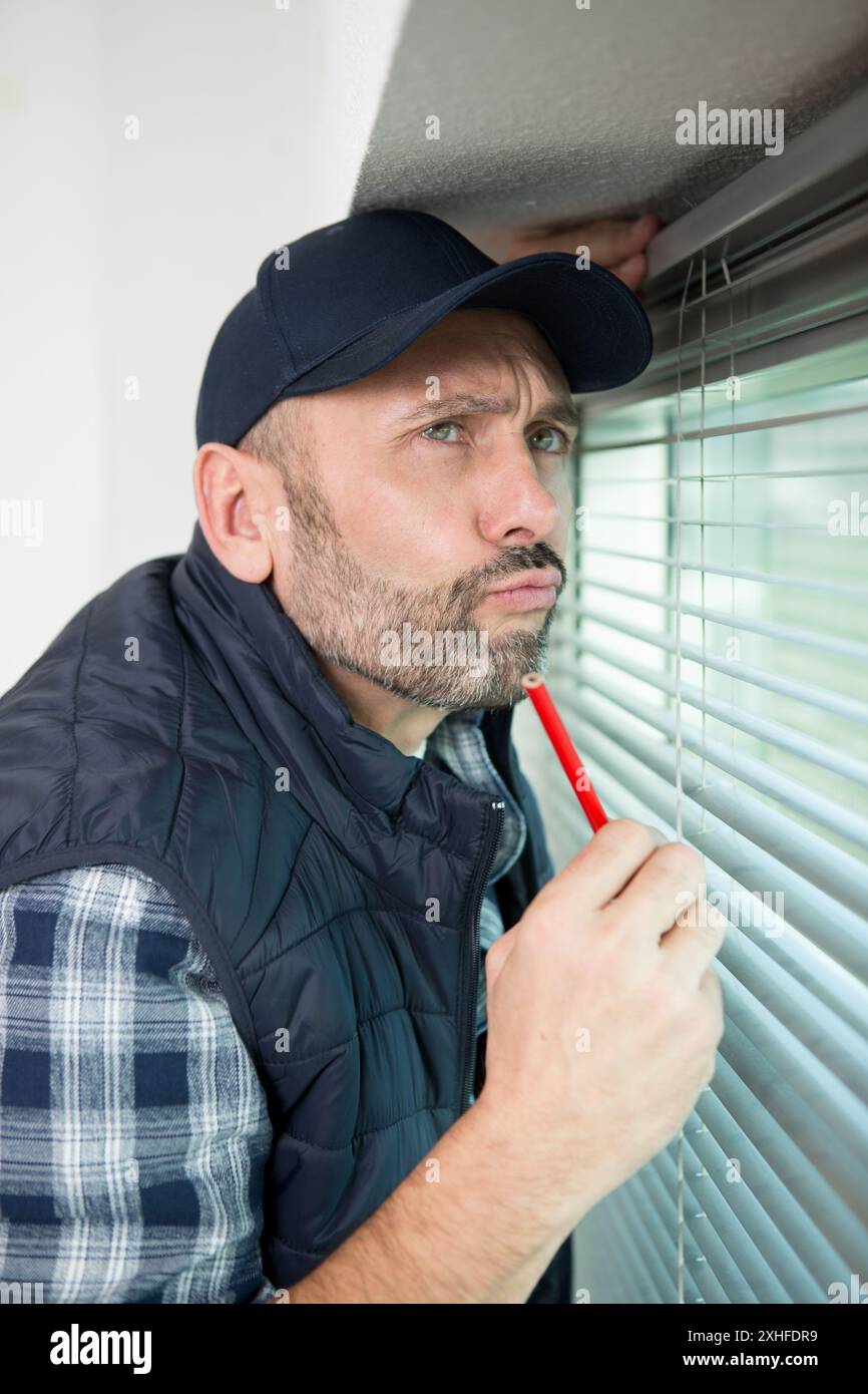 male contractor installing window blinds Stock Photo
