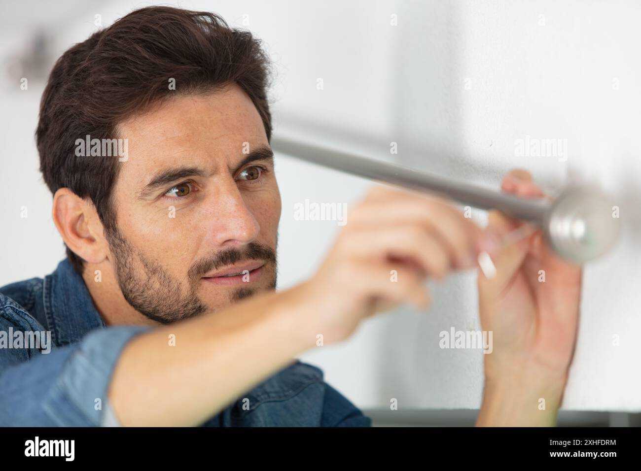 worker installing window curtain rod on the wall Stock Photo