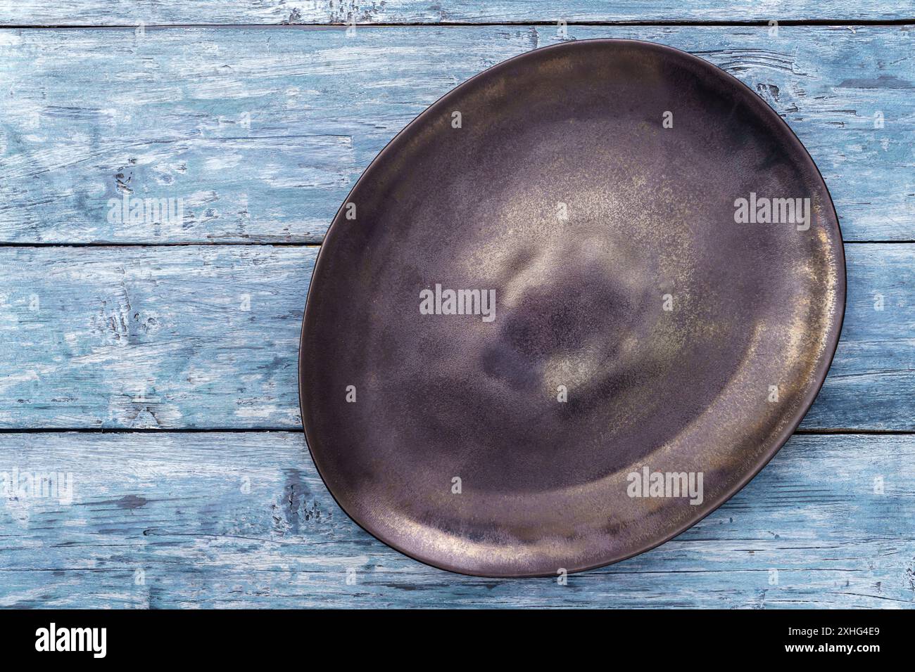 Empty black irregular plate on blue background. Top view, with copy space Stock Photo