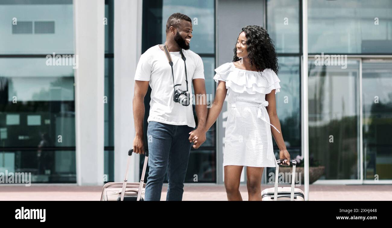 Happy Black Couple Walking Through Airport With Luggage Stock Photo - Alamy