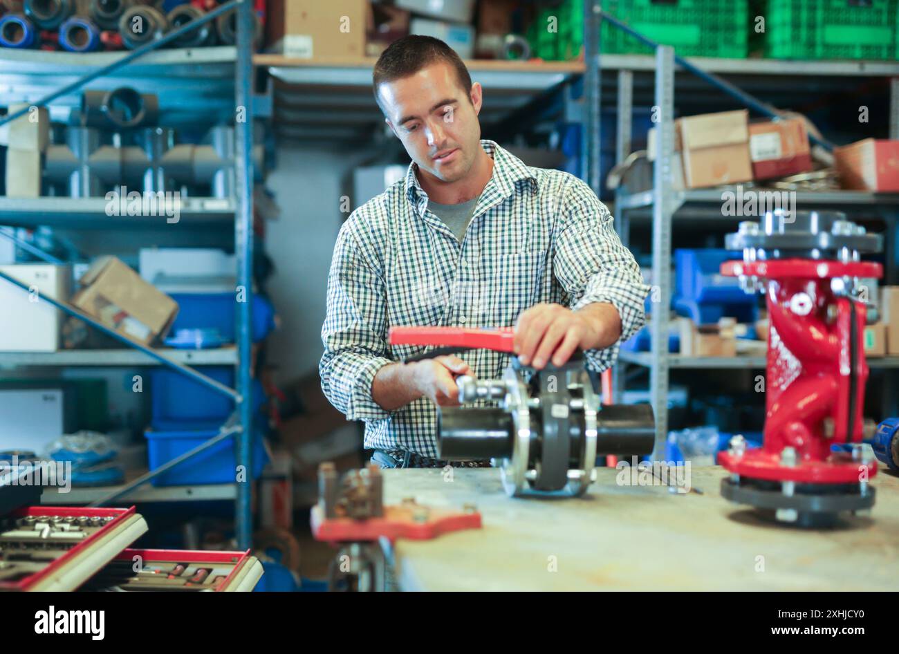 Factory worker assembles shutoff valves using various tools indoor ...