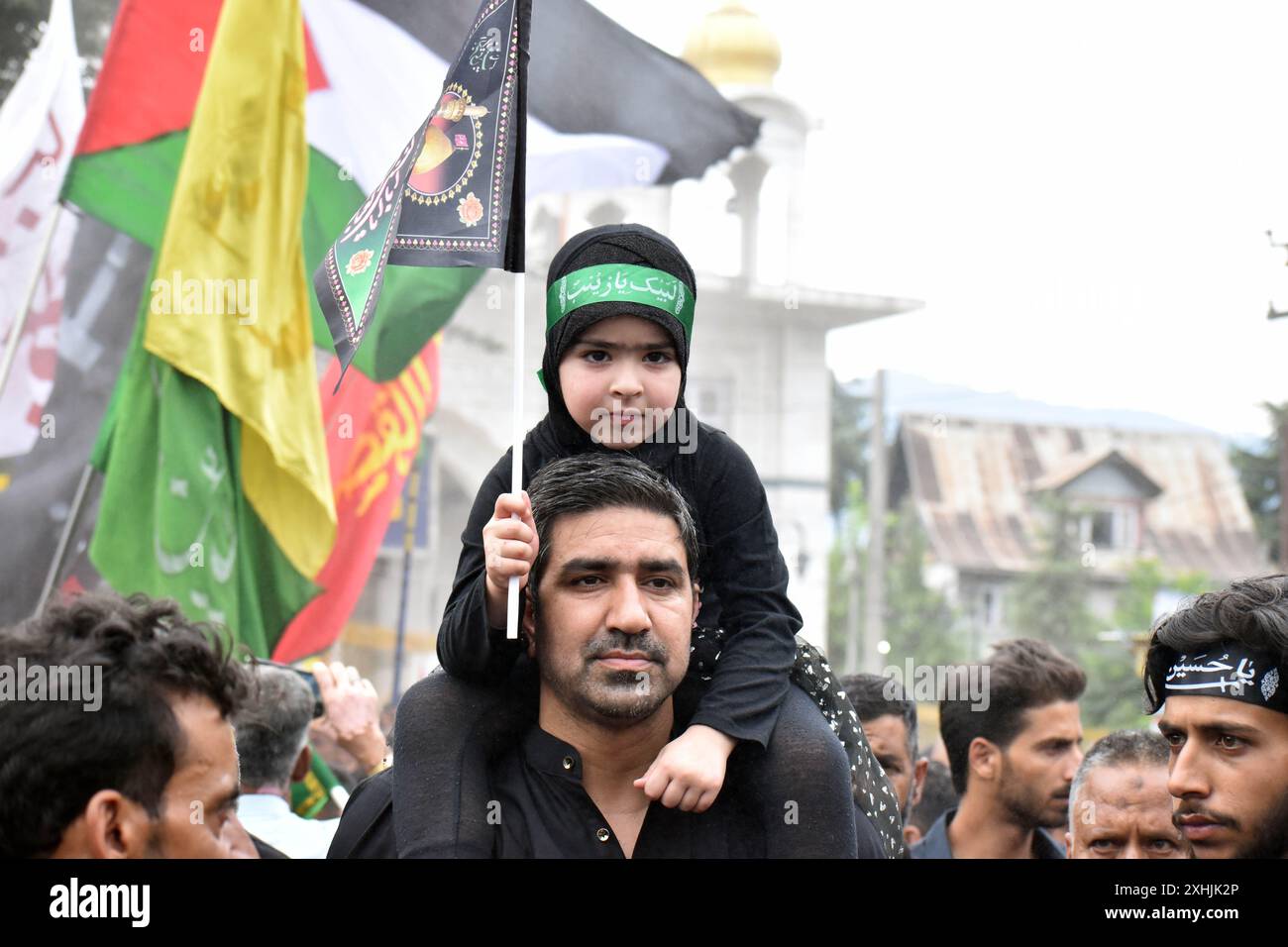 Srinagar, India. 14th July, 2024. A Kashmiri Shiite muslim carries her ...