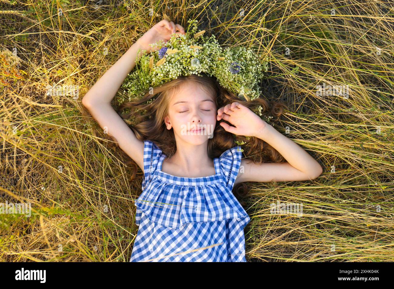 Cute little girl wearing wreath made of beautiful flowers on green ...