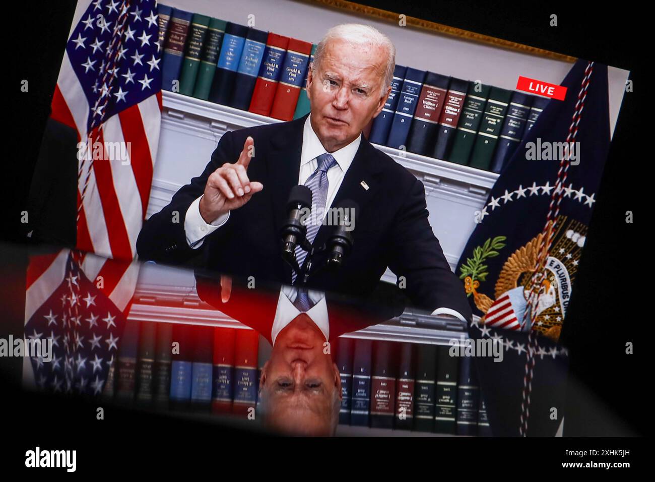 In this photo illustration, a screen shows current US President Joe Biden speaking from the Roosevelt Room of the White House in Washington. President Biden and Vice President Harris held a briefing to discuss the incident and express support for Donald Trump. Biden called for an investigation into the incident and expressed condolences to the family of the victim who rushed to protect the family during the shooting and thereby died. The suspect in the shooting, 20-year-old Thomas Matthew Crooks, was arrested and charged with attempted murder. Stock Photo