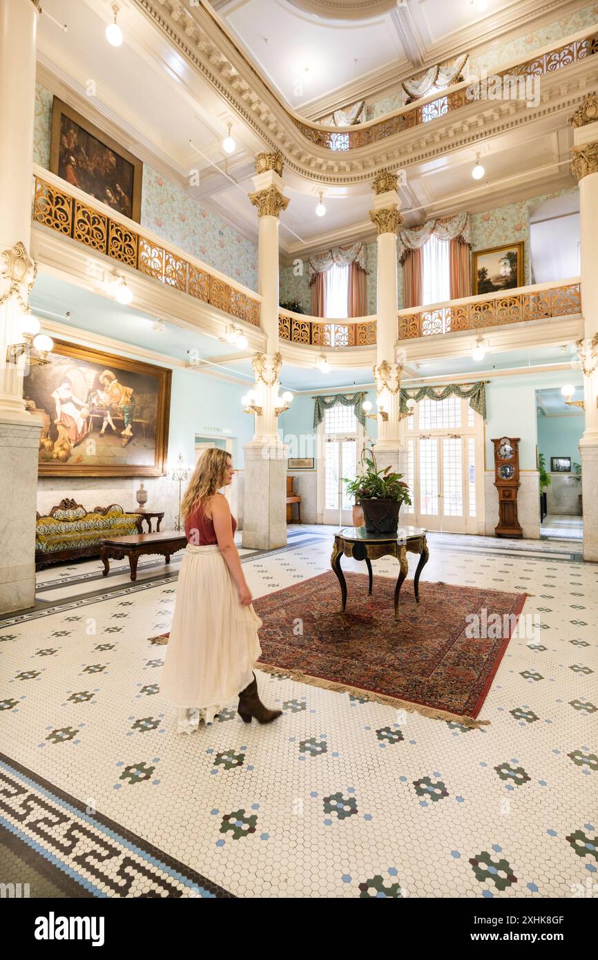 Female guest walks around the gilded lobby atrium where famous people ...