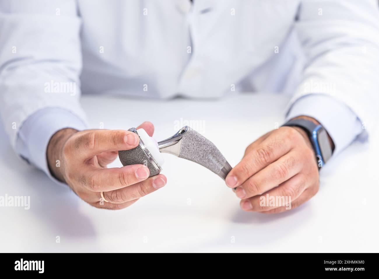 Close-up of an orthopedic surgeon's hands holding and demonstrating a hip prosthesis. Ideal for medical and healthcare-related themes. Stock Photo