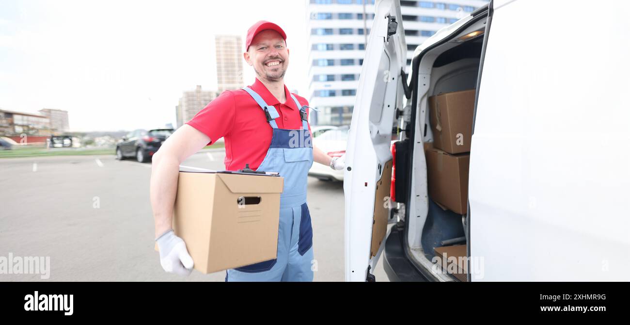 Smiling courier with parcels near delivery van Stock Photo