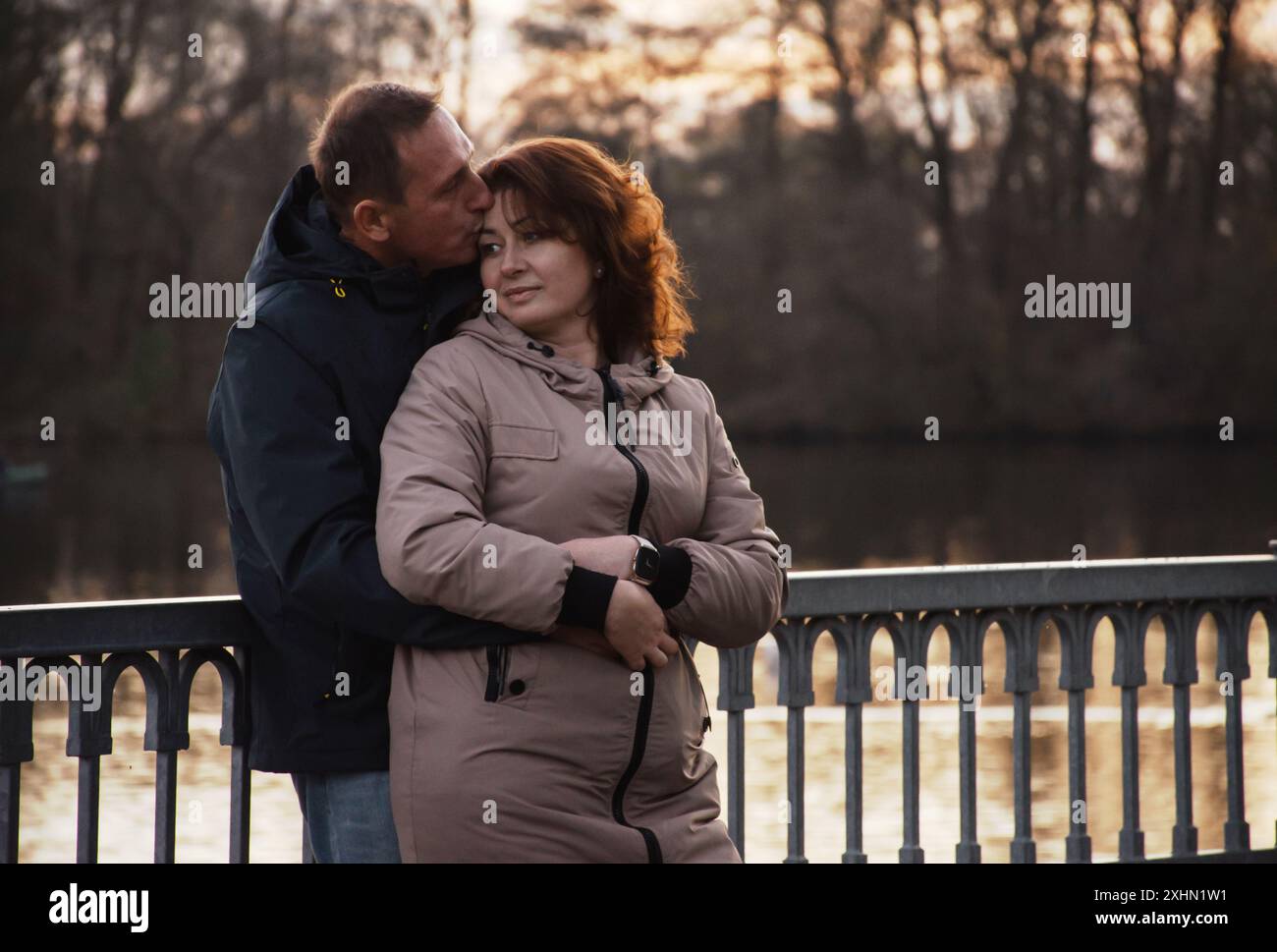 a happy married couple walks along the embankment in the evening, hugs, spends time together. Stock Photo