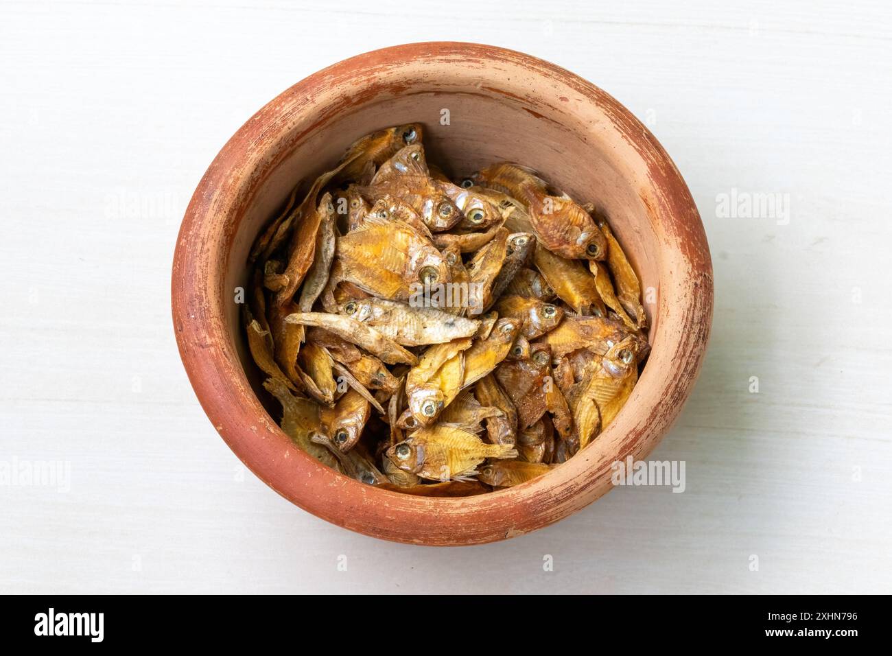 Dried rupchanda shutki or chinese pomfret fish in earthen pot on light white wooden background. Stock Photo