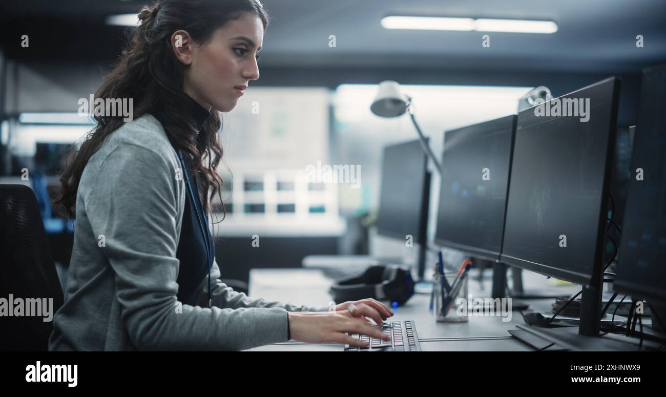 Young Female Artificial Intelligence Engineer Working on Computer in a Technological Office. Young Specialist Writing Software Code for an Innovative Big Data Blockchain Project Stock Photo