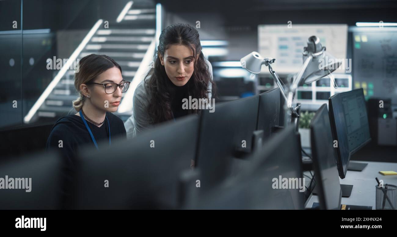 Young Female Software Developer Working on Computer Together with a Friendly Colleagues. Female Asking Advice from a Manager About a Solution for Their Collaborative Tech Project Stock Photo
