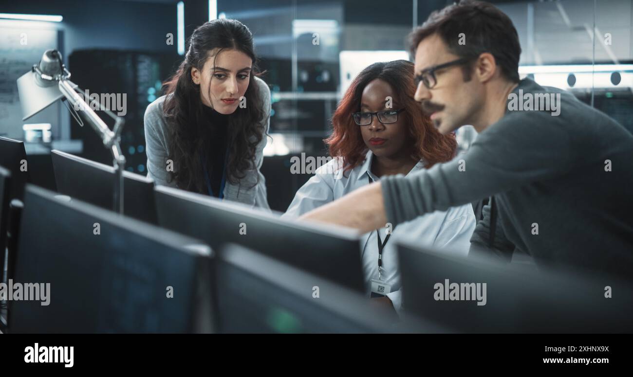 Group of Empowered Multicultural Specialists Working in a Research Center, Using Computer to Collaborate on Advanced Software, Develop Artificial Intelligence Interface and Cloud-Based Blockchain Stock Photo