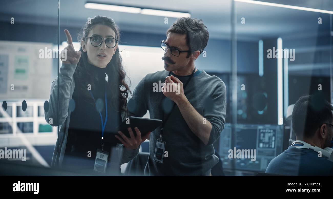 Multicultural Chief Technology Officer Talking to Software Developer, Discussing Neural Network Updates in High Tech Research and Development Facility. Professional Computer Specialists at Work Stock Photo