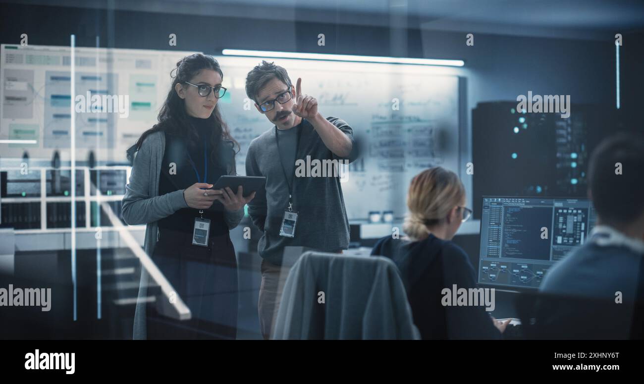 Multicultural Chief Technology Officer Talking to Software Developer, Discussing Neural Network Updates in High Tech Research and Development Facility. Professional Computer Specialists at Work Stock Photo