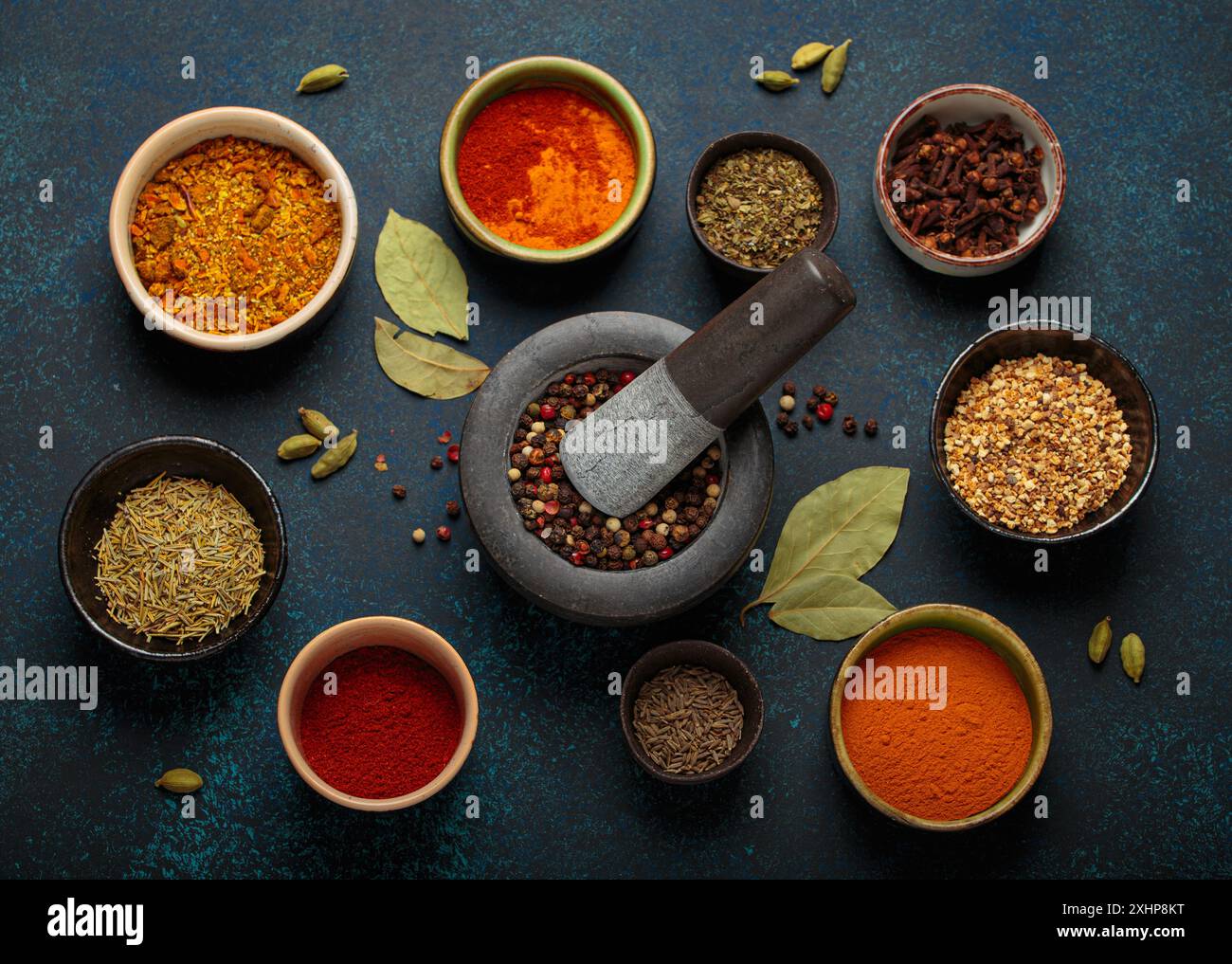 Mortar and pestle surrounded by colorful spices on dark background Stock Photo