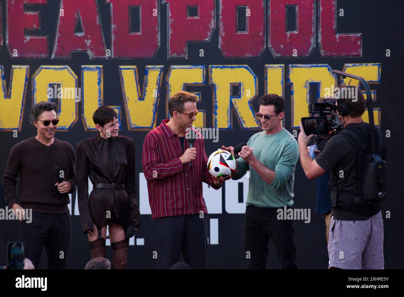 Stage presentation with Steven Gaetjen and Ryan Reynolds, Hugh Jackman, Emma Corrin, Shawn Levy (director) signing a ball for the winner of a lucky Stock Photo