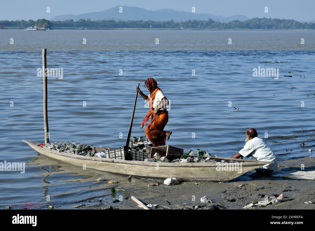 Rag picker collecting plastic bottle and other plastic materials in a boat from the bank of Brahmaputra River in Guwahati, Assam, India on Monday Stock Photo