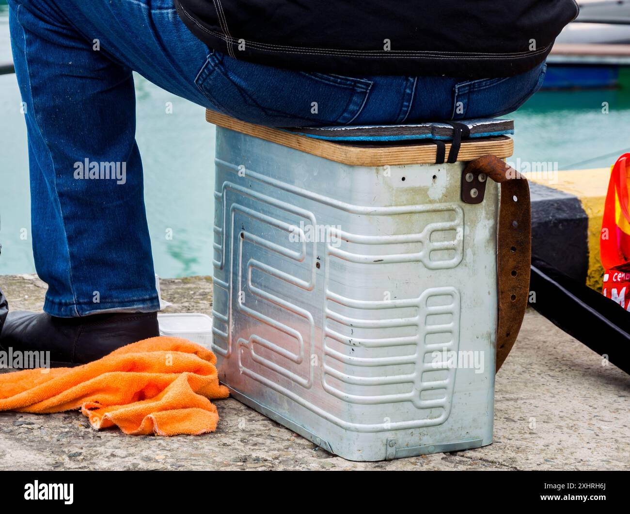 A man sits on a fishing box from a refrigerator freezer heat exchanger Stock Photo