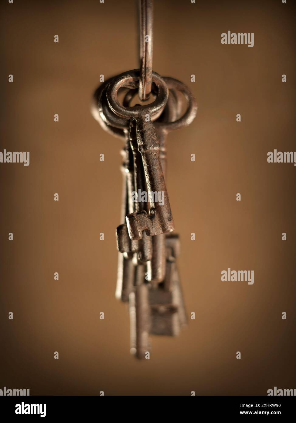 old keys hanging from the front on sepia background Stock Photo