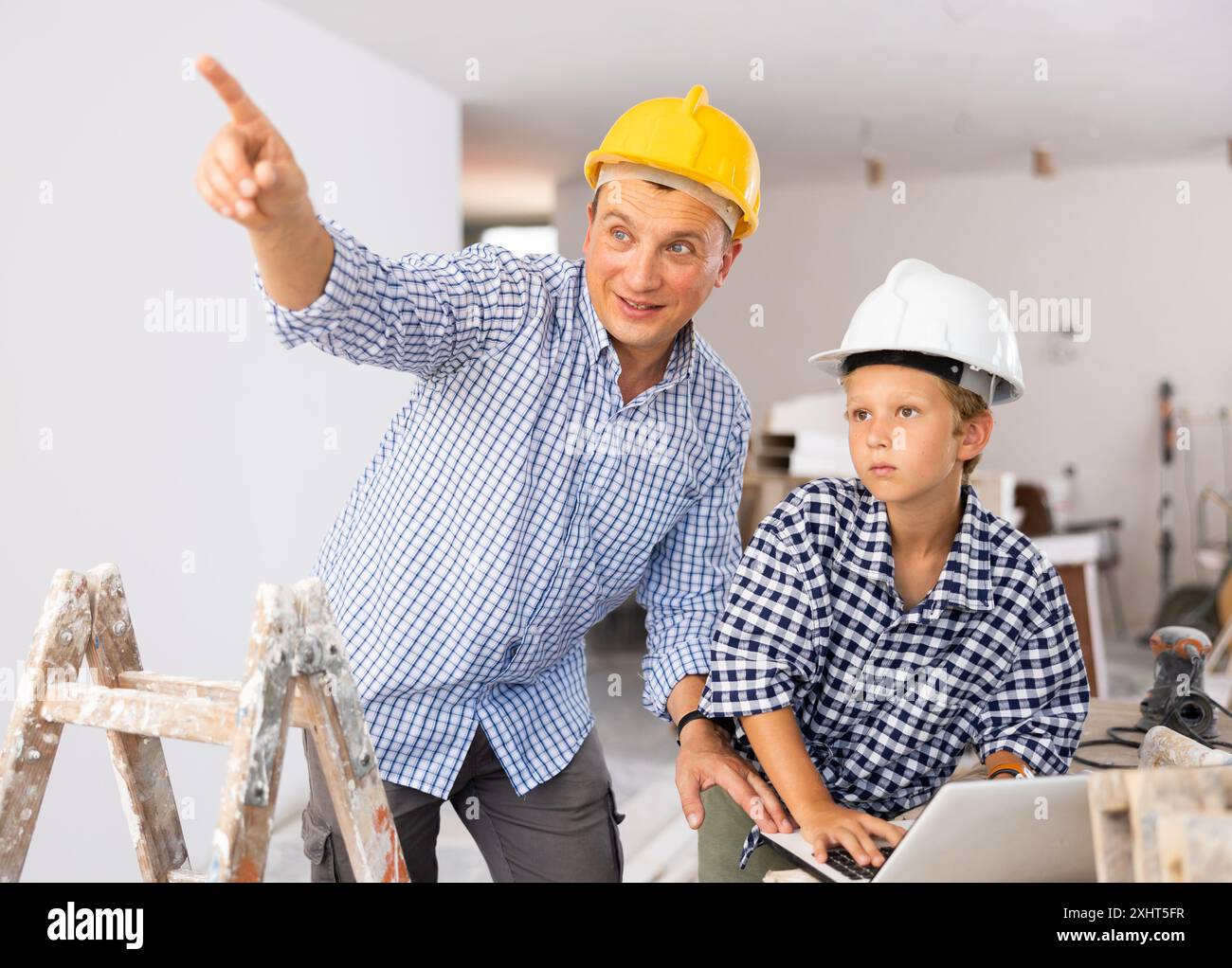 Man architect and boy using laptop while discussing working process in house being renovated Stock Photo