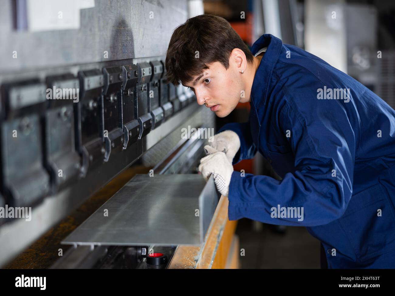 Young worker works on sheet bending machine at metallurgical plant ...