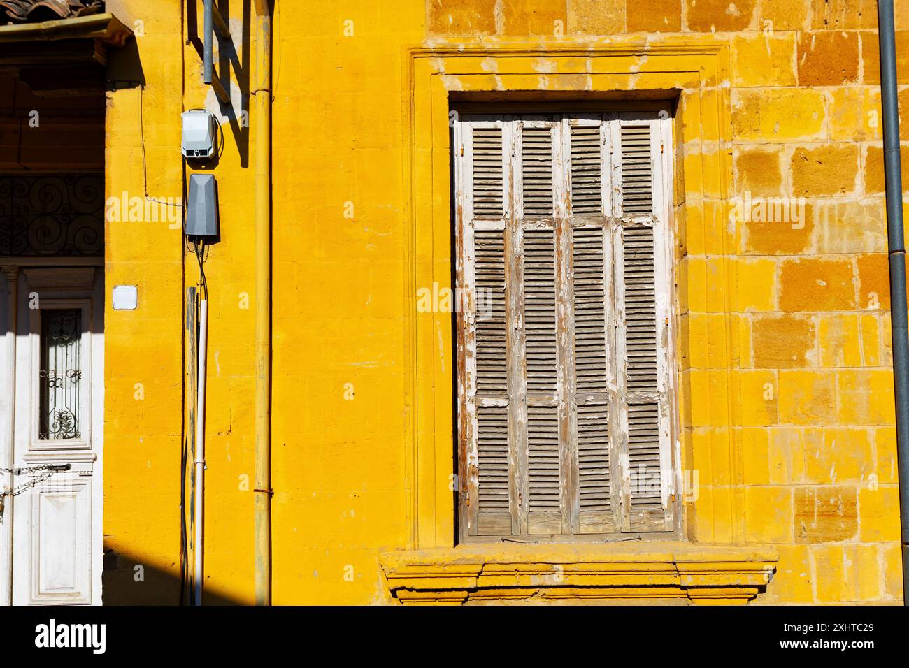 Yellow wall building with a window that is closed. Old house has a rustic appearance Stock Photo