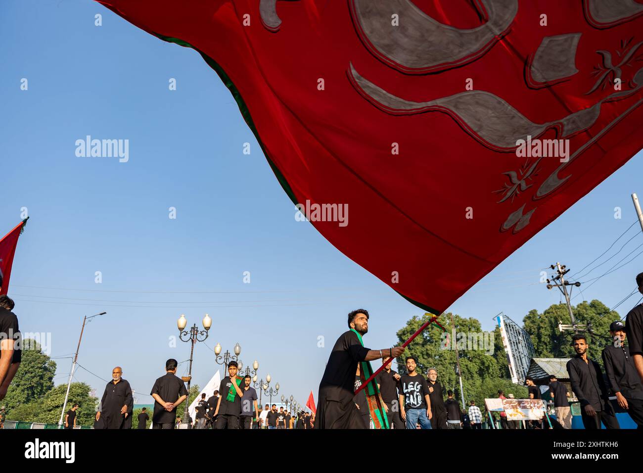 A Kashmiri Shia Muslim man waves a large religious flag inscribed with ...