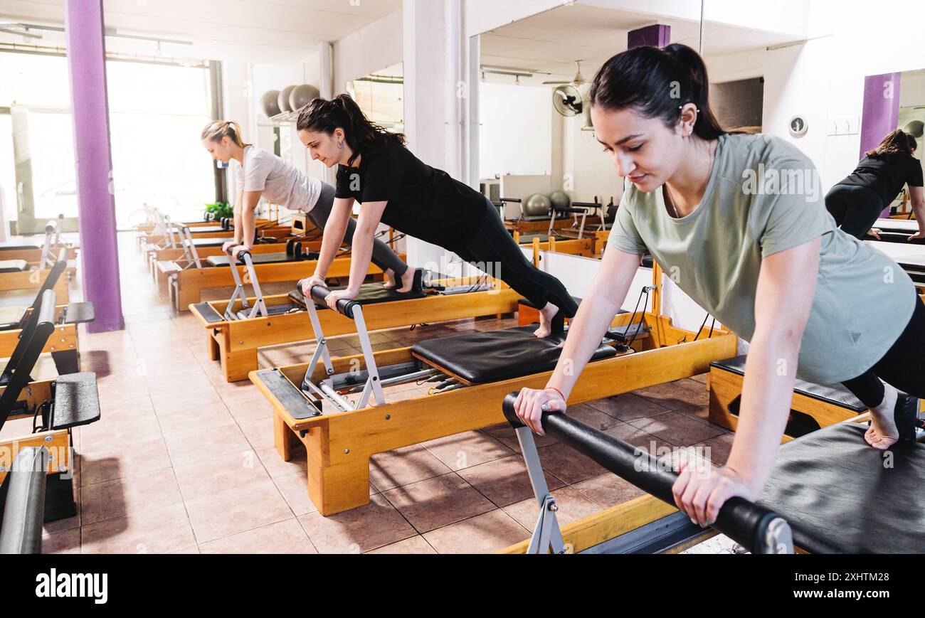 Group of young women exercising on reformer pilates bed. Stock Photo