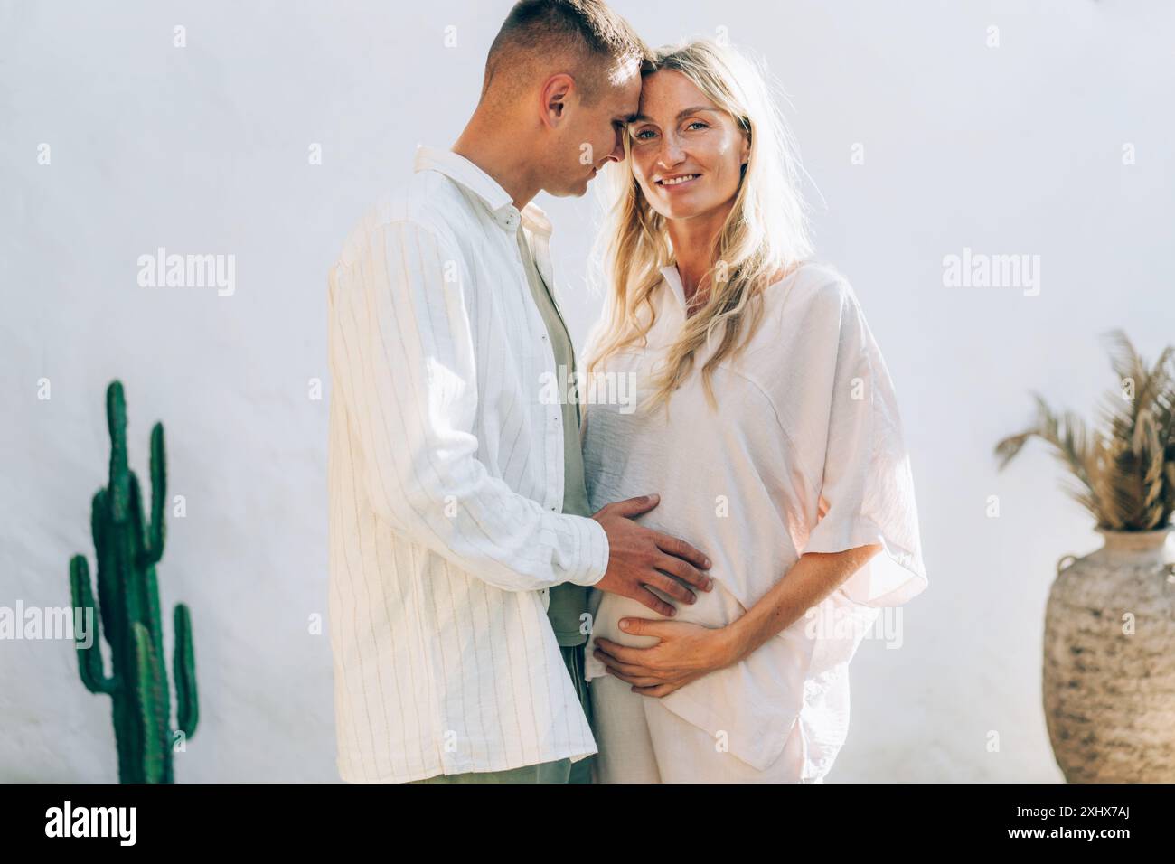 Happy man hugging his pregnant wife outside against a white wall Stock ...