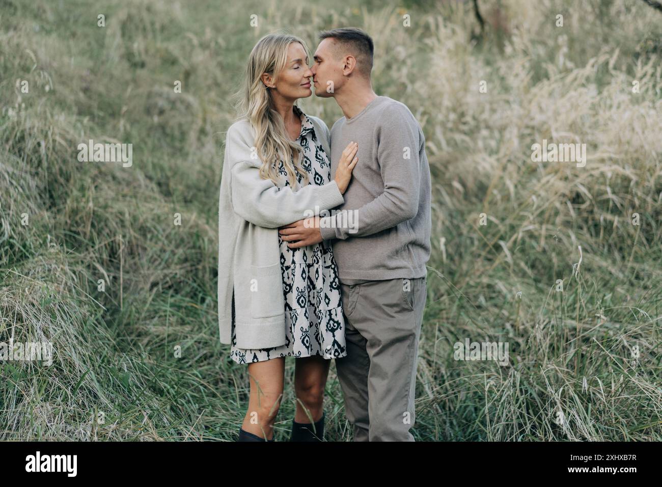 A young man kisses and hugs his pregnant wife while standing in the ...