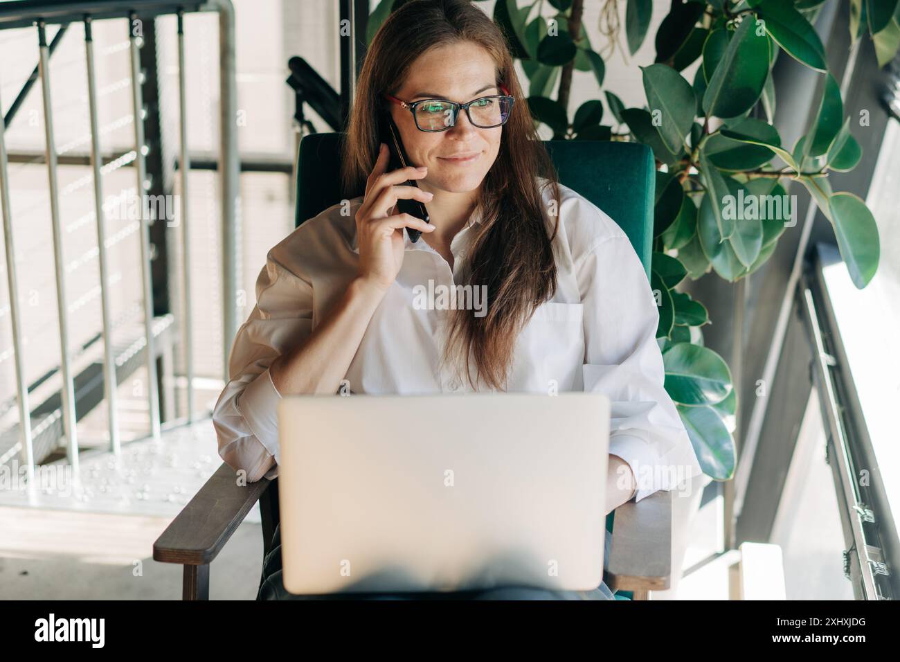 Young business woman talking on the phone and working using a laptop. Stock Photo