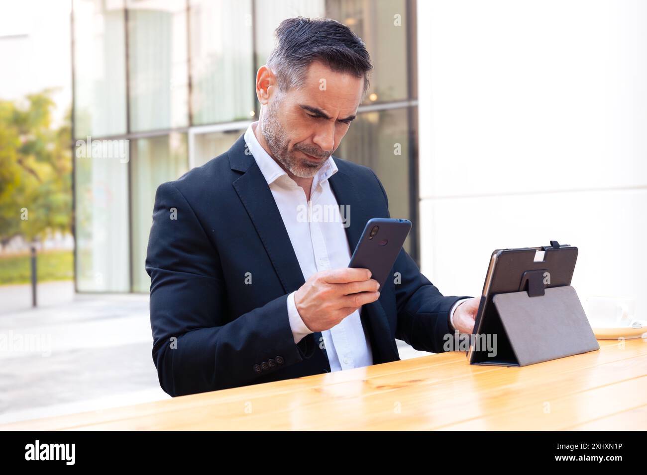 Businessman using an app on his smartphone and standing Stock Photo
