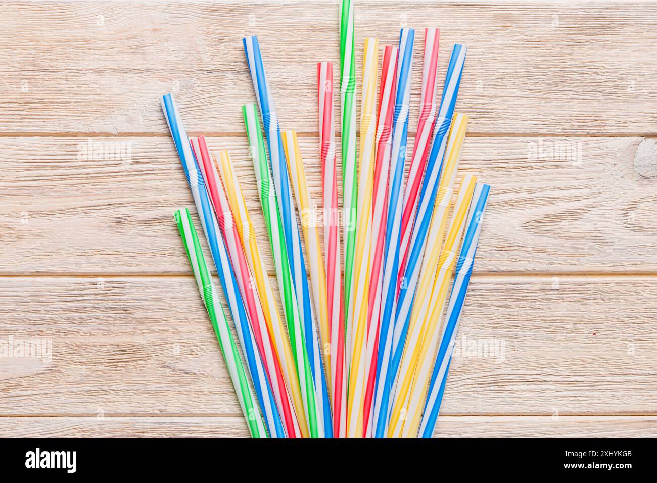 many multi-colored plastic tubes for cocktail on Colored background, top view. Stock Photo
