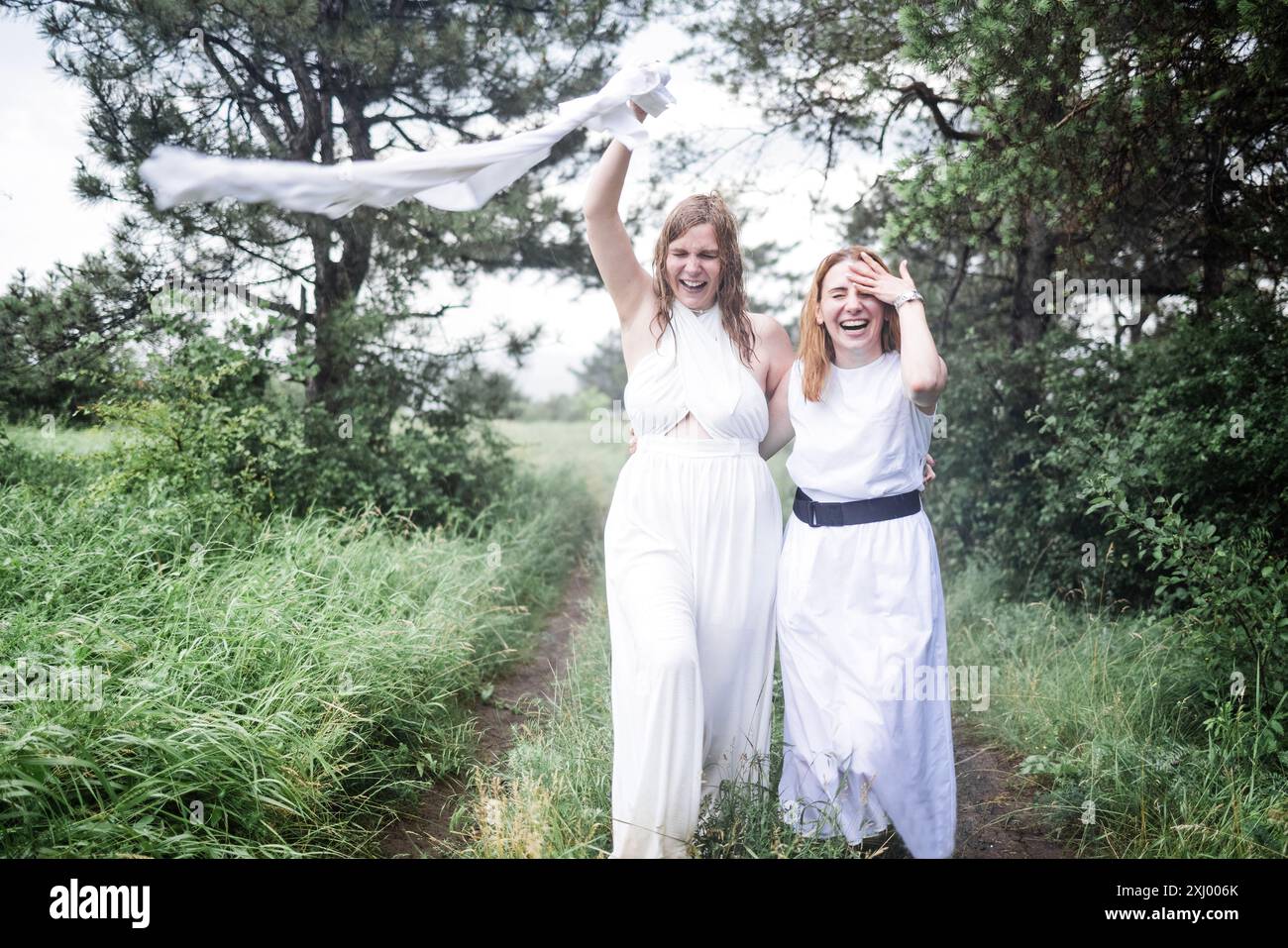 Two charming girls in white dresses are running in the summer rain. The ...