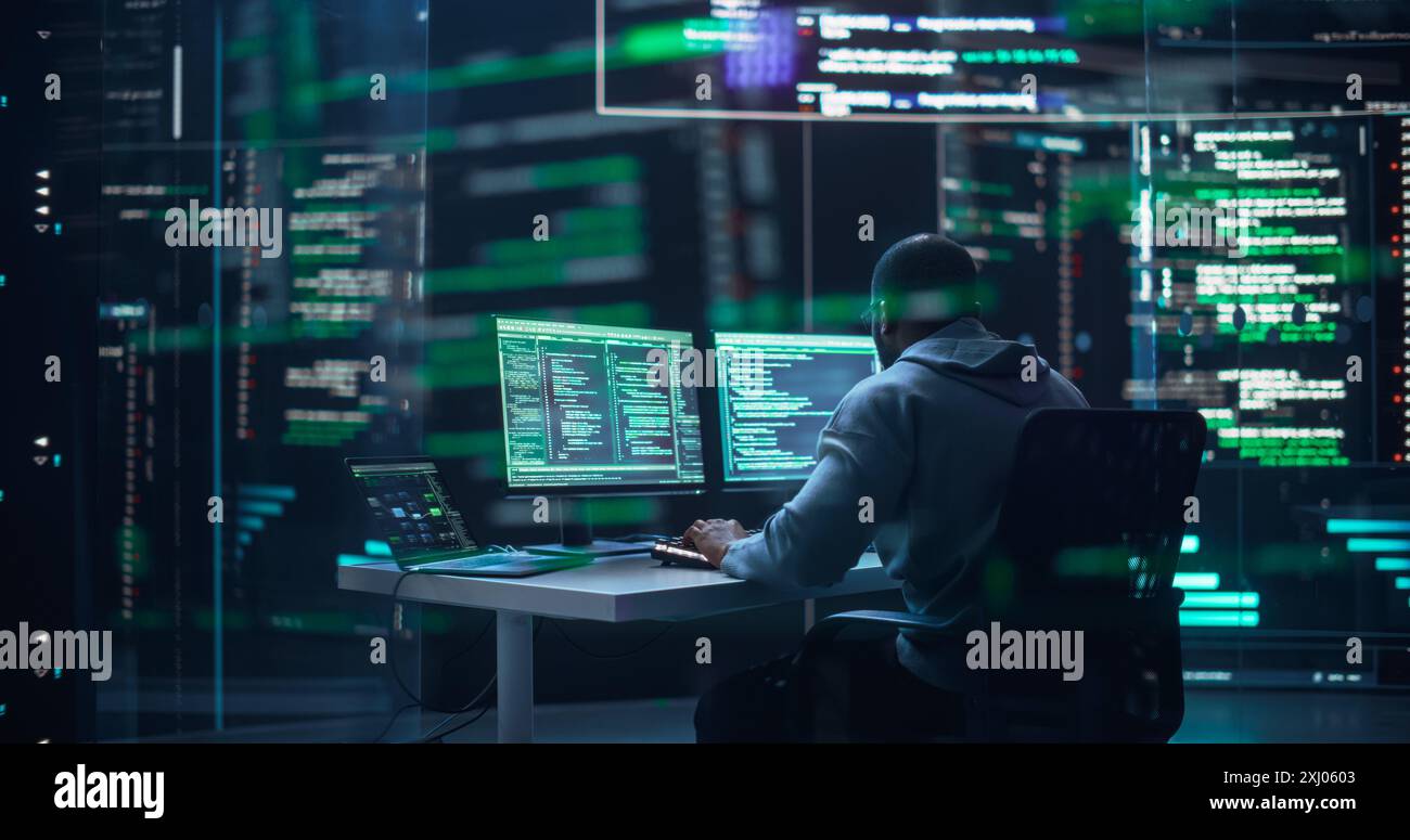 Black Male Developer Typing on Computer, Surrounded by Transparent Screens Showing Code Lines. Professional Programmer Creating Complex Software, Running Coding Tests. Futuristic Programming. Stock Photo