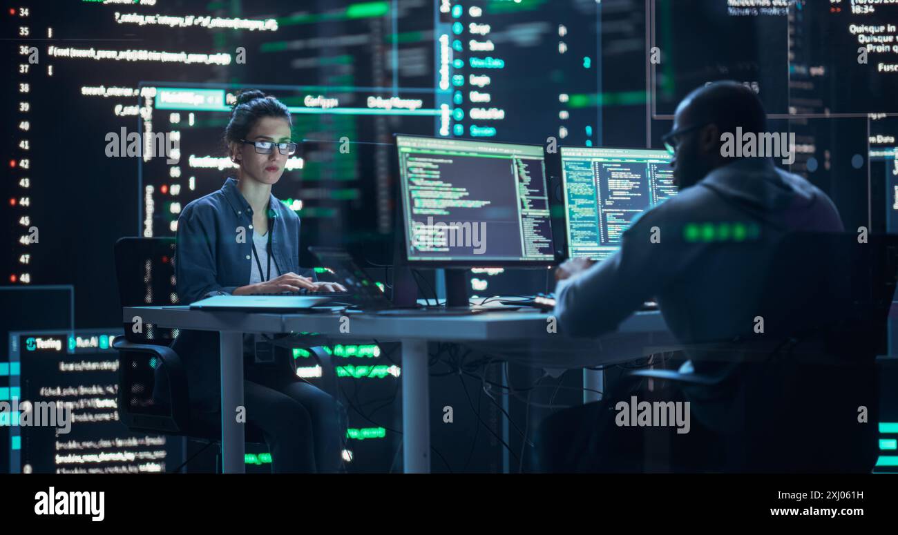 Diverse Young Man and Woman Working on Desktop Computers, Surrounded by Big Screens Displaying Code Lines. Professional Computer Engineers Developing Autonomous Algorithm for Generative AI. Stock Photo