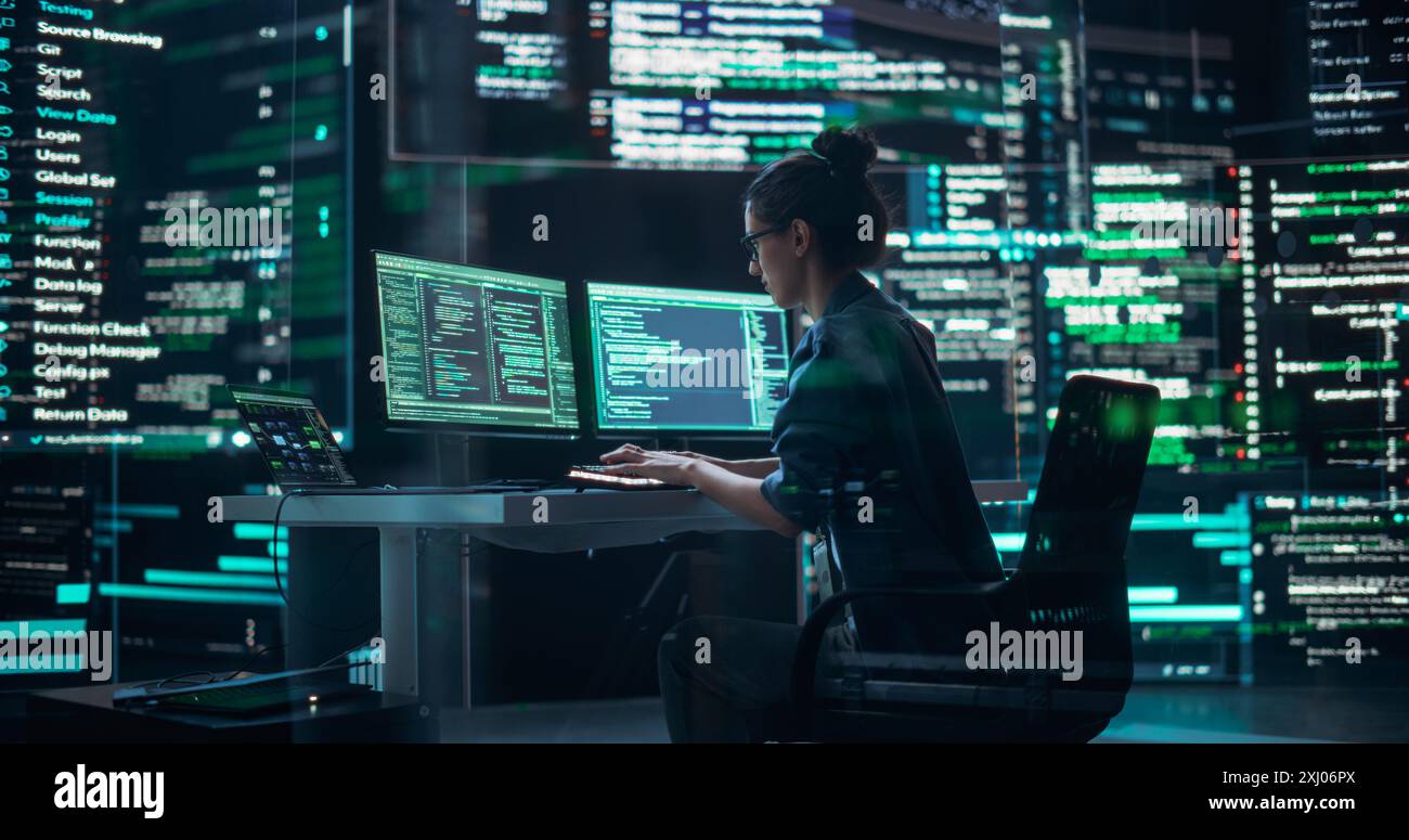 Female Developer Thinking and Typing on Computer, Surrounded by Big Screens Showing Coding Language. Professional Programmer Creating Software, Running Coding Tests. Futuristic Concept of Programming Stock Photo