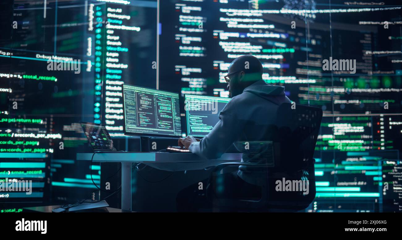 Black Male Developer Thinking and Typing on Computer, Surrounded by Big Screens Showing Coding Prompts. Professional Programmer Creating Software, Running Coding Tests. Futuristic Programming Concept Stock Photo