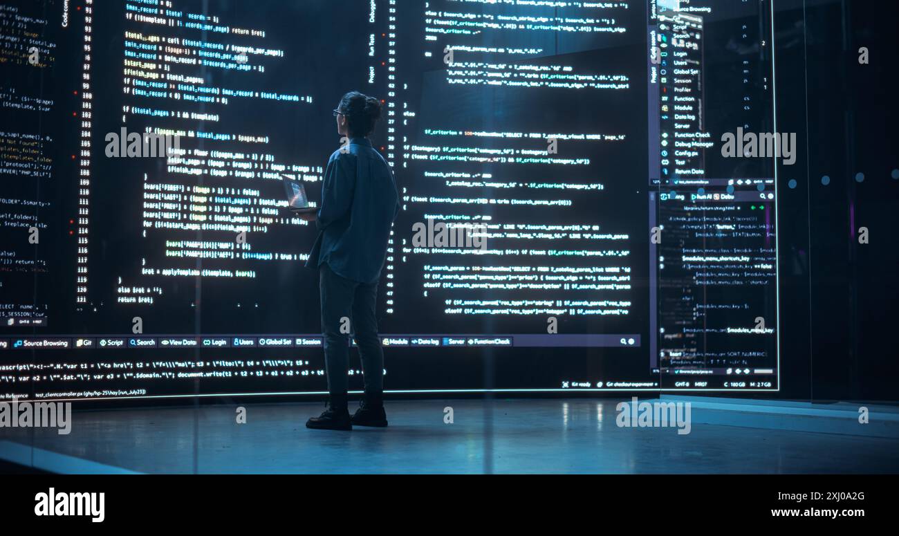 Portrait of Young Woman Working on Laptop Computer, Looking at Big Digital Screen Displaying Back-end Code Lines. Professional Programmer Developing a Big Data Interface Software Project Stock Photo