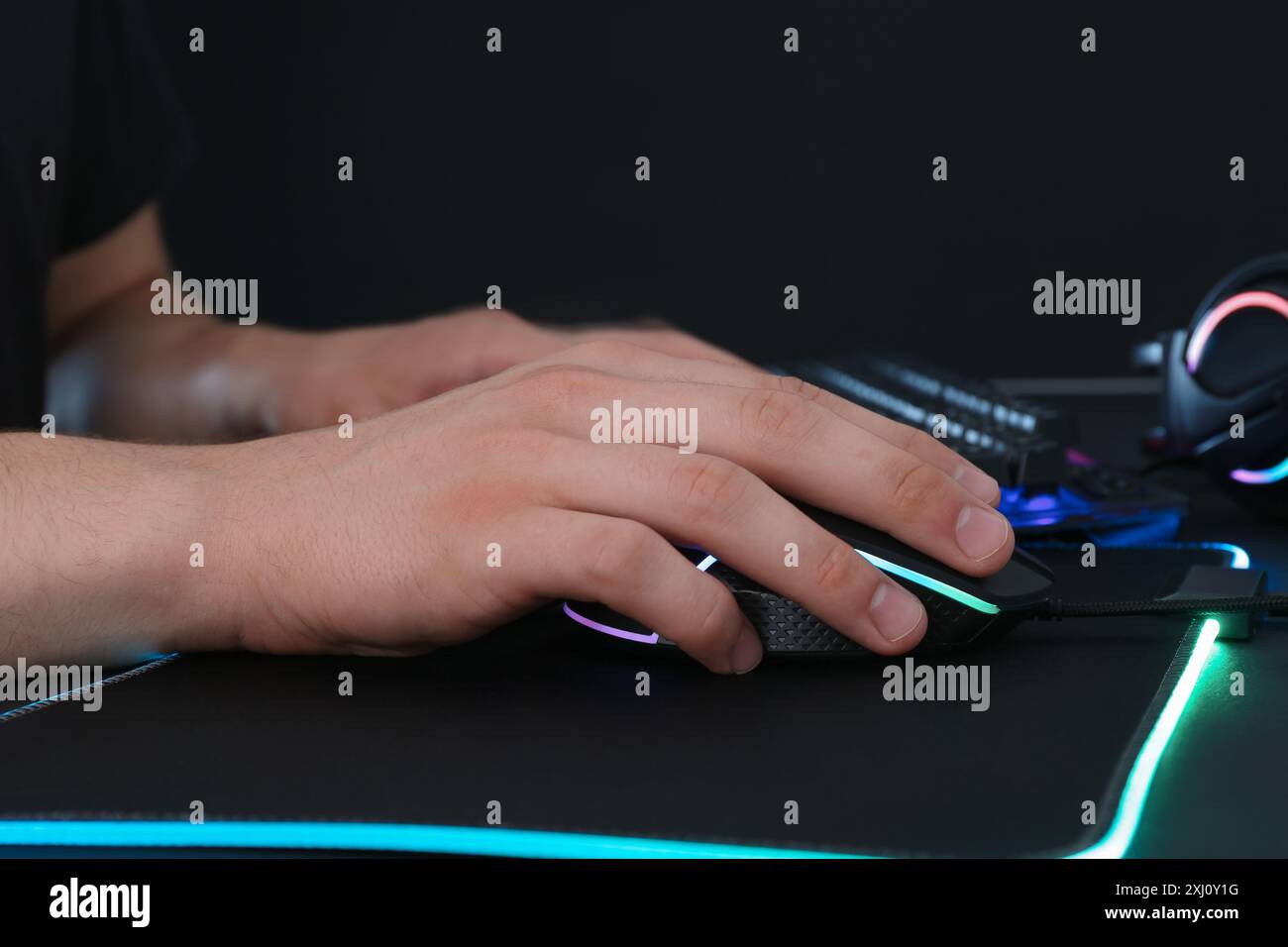 Gamer using modern wired computer mouse at black table, closeup Stock Photo