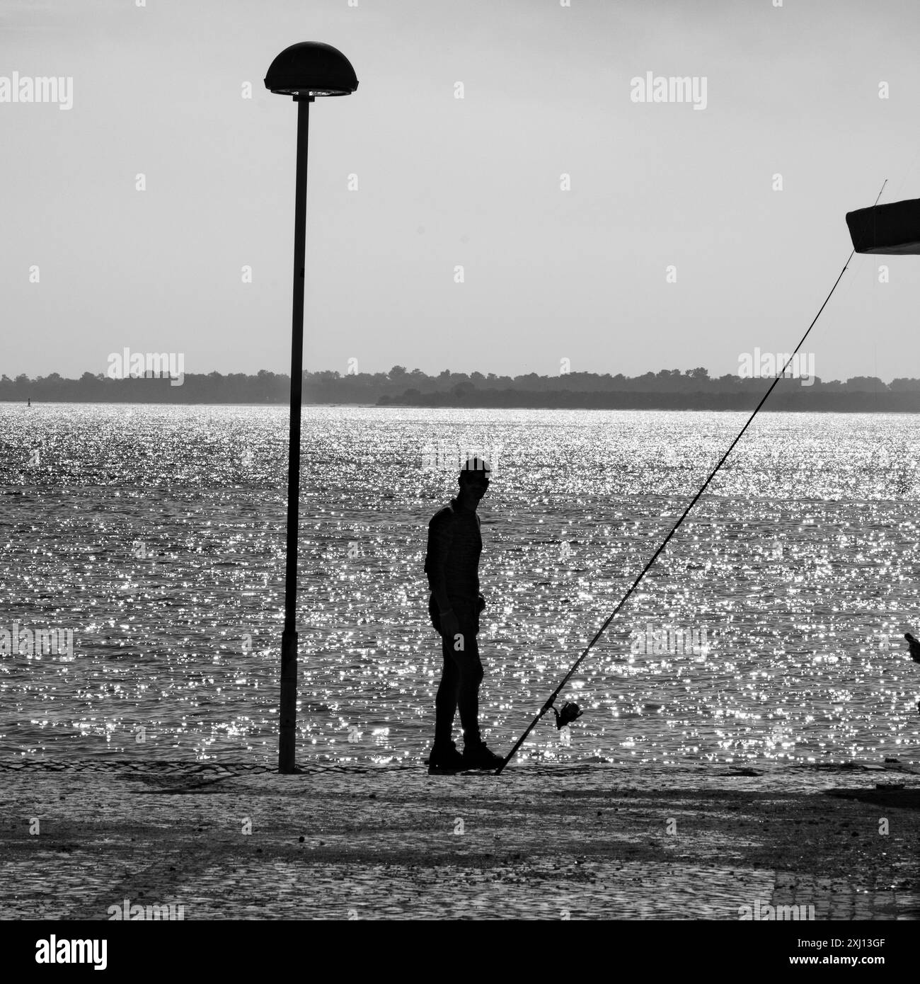 A fisherman standing along the shoreline of Setúbal which is a busy port and industrial city in Portugal that boasts an extensive history and rich sea Stock Photo