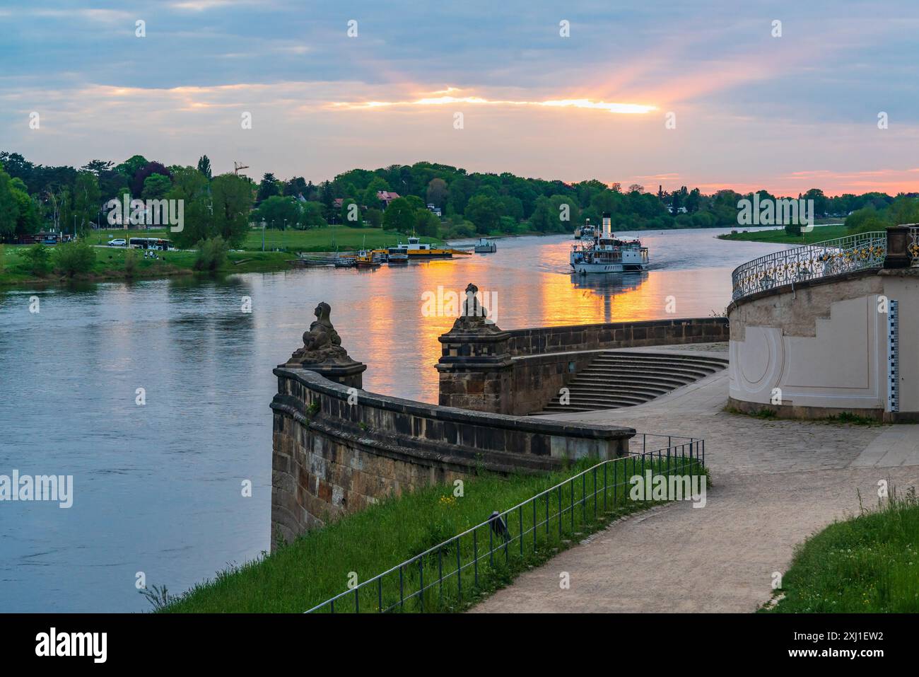 Sunset on the Elbe River in the famous city of Dresden. Tourist, pleasure boats slowly sail along the river at sunset past a beautiful staircase in th Stock Photo