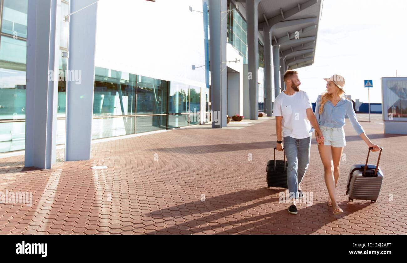 Happy couple walking in front of airport terminal building Stock Photo ...