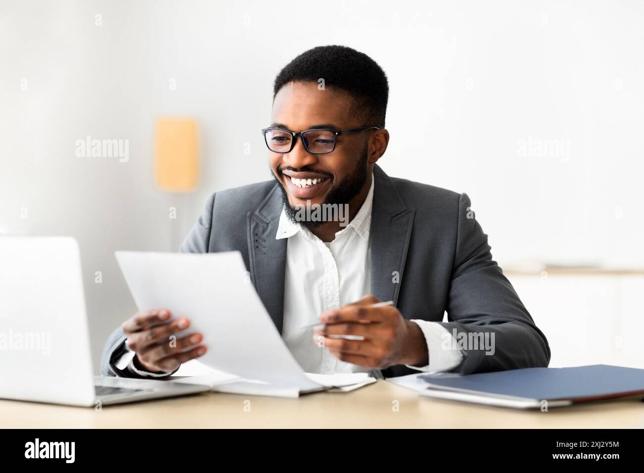 Cheerful black businessman checking reports and making notes Stock Photo