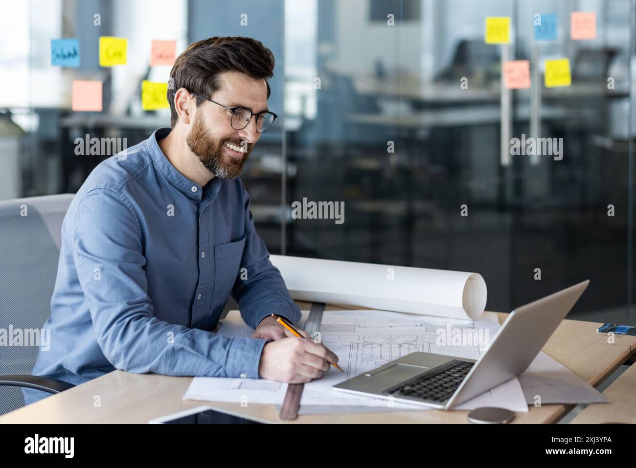 A young smiling male architect, engineer and developer works in the ...